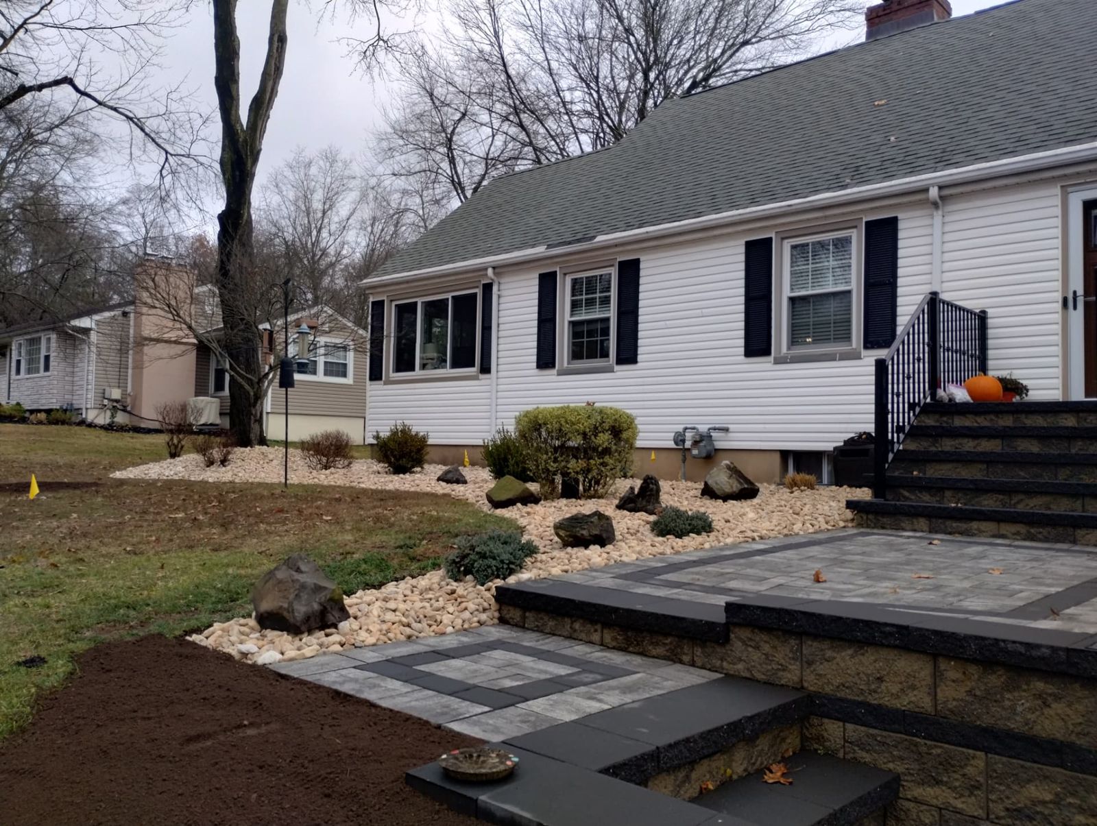 Front yard hardscape build with paver landing, steps and river rock beds in New Jersey